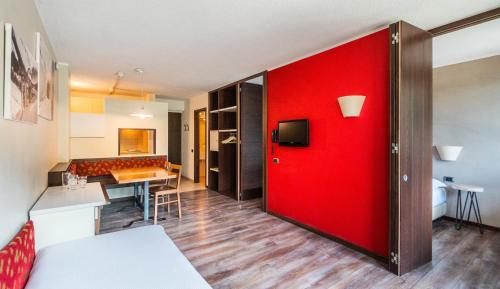 a red door in a living room with a kitchen at Ambiez Residencehotel in Madonna di Campiglio