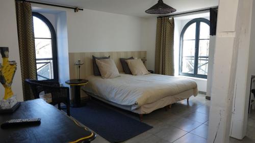 a bedroom with a bed with two windows and a desk at Ilot du Moulin in Mordelles