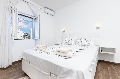 um quarto branco com uma cama branca e uma janela em Apartments Natasa em Radovići