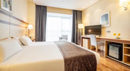 a hotel room with a large bed and a desk at Ilunion Pio XII in Madrid