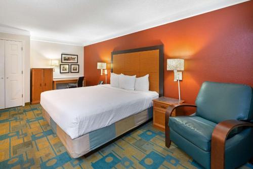 um quarto de hotel com uma cama e uma cadeira azul em La Quinta Inn by Wyndham Phoenix Sky Harbor Airport em Tempe