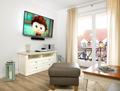 sala de estar con TV de pantalla plana en la pared en Ostsee Residenz Meeresblick Strandjuwel en Insel Poel