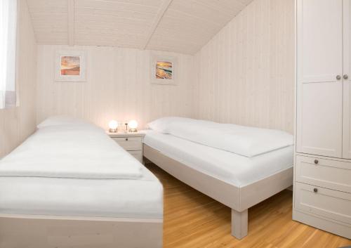 Duas camas num pequeno quarto com mobiliário branco em Dänische Ferienhäuser am Salzhaff Haus Strandhafer em Gollwitz
