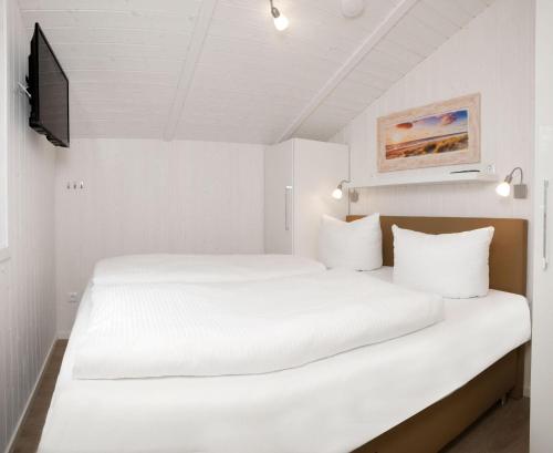 a white bedroom with two beds and a tv at Dänische Ferienhäuser am Salzhaff Haus Strandbrise in Malchow