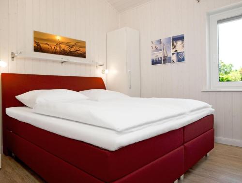ein großes Bett in einem Schlafzimmer mit einem roten Kopfteil in der Unterkunft Dänische Ferienhäuser am Salzhaff Haus Midsommer in Malchow