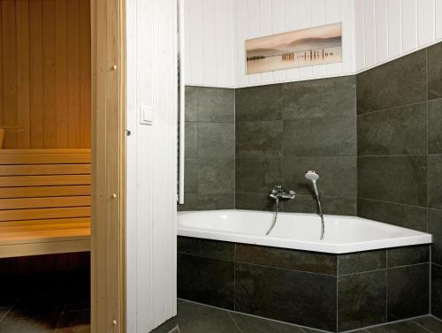 eine Badewanne im Bad mit Dusche in der Unterkunft Dänische Ferienhäuser am Salzhaff Haus Midsommer in Malchow