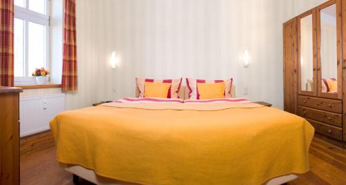 a bedroom with a large bed with a yellow blanket at Einhusen Gute Stube in Insel Poel