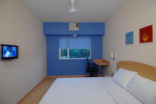 a bedroom with a bed and a blue wall at Ginger Pondicherry in Puducherry