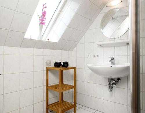 a white bathroom with a sink and a skylight at Haus Meernixe in Kaltenhof