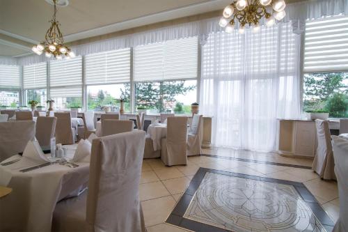 a dining room with white tables and chairs and windows at Bristol Kralovska Vila in Karlovy Vary