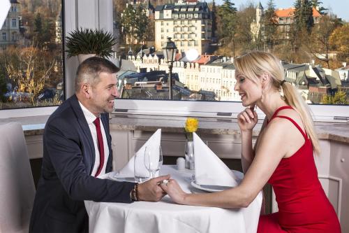 a man and woman sitting at a table with paper boats at Bristol Kralovska Vila in Karlovy Vary