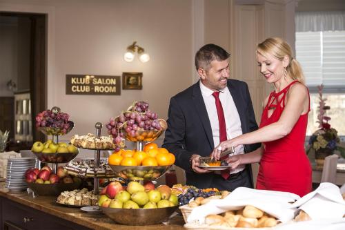 a man and woman standing in front of a buffet of fruit at Bristol Kralovska Vila in Karlovy Vary