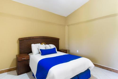 a bedroom with a bed with blue and white sheets at Grand View Suites in Manzanillo
