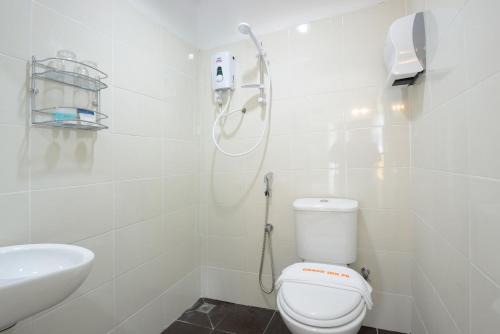 Baño blanco con aseo y lavamanos en Grand Inn - Penang Road, en George Town
