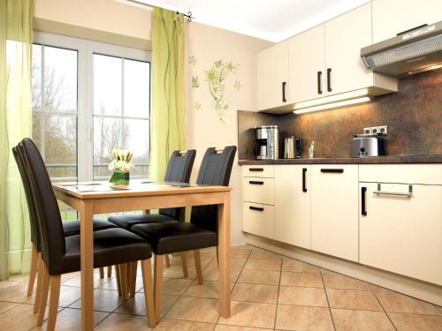 une cuisine avec une table en bois et des chaises noires dans l'établissement Gollwitzer Park Seeperle, à Poel