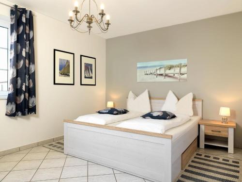 een slaapkamer met een wit bed en een kroonluchter bij Gollwitzer Park Ableger in Insel Poel