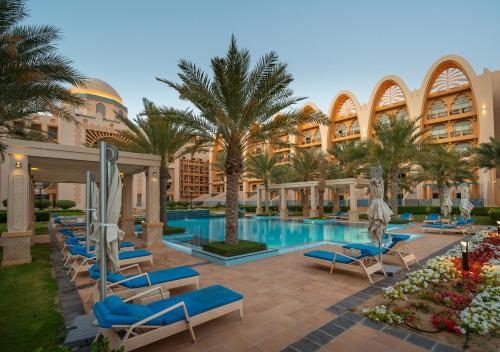 un complexe avec une piscine, des palmiers et des chaises longues dans l'établissement GLOBALSTAY at Sarai Apartments Beachfront Paradise with Pool and Gym, à Dubaï