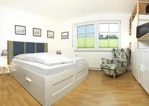 1 dormitorio blanco con 1 cama y 1 silla en Appartements Am Reiterhof Am Reitstall, en Poel