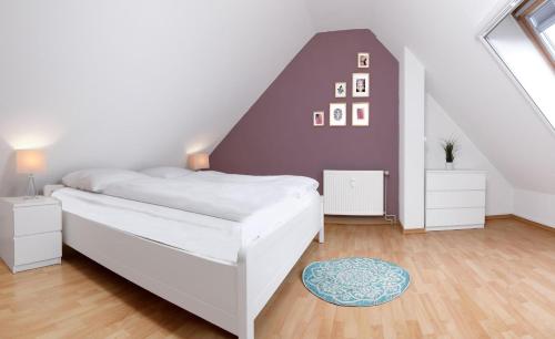 - une chambre avec un lit blanc et un mur violet dans l'établissement Appartements Am Reiterhof Meerzeit, à Timmendorfer Strand