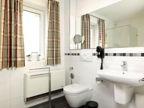 a white bathroom with a sink and a toilet at Ferienwohnungen Fischerstieg Hafenblick in Timmendorf