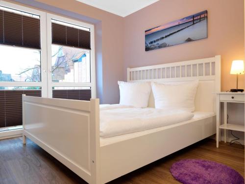 een wit bed in een kamer met 2 ramen bij Haus Südwester Hummer in Insel Poel