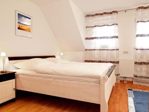 a white bedroom with a bed and windows at Reihenhäuser Timmendorf Strand Haus Utkiek in Timmendorf