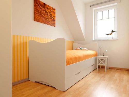 ein Schlafzimmer mit einem Bett mit einer orangefarbenen Decke in der Unterkunft Doppelhäuser Timmendorf Strand Haus Taun Lüchttorm in Insel Poel
