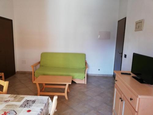 sala de estar con sofá verde y mesa en Le Coltie - affittacamere e appartamenti, en Venturina Terme