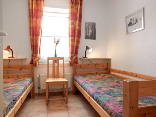 une chambre avec deux lits et une chaise et une fenêtre dans l'établissement Buchenweg Whg.24, Sommerfeld, EG li, à Poel