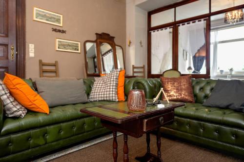 a living room with a green couch and a table at B&B Villa Belle Epoque in Durbuy