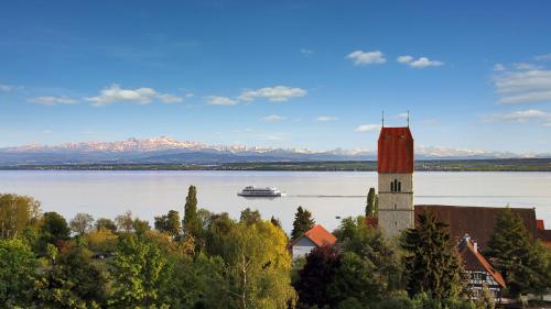 a cruise ship on the water with a building and a lighthouse at Hotel Mohren in Hagnau