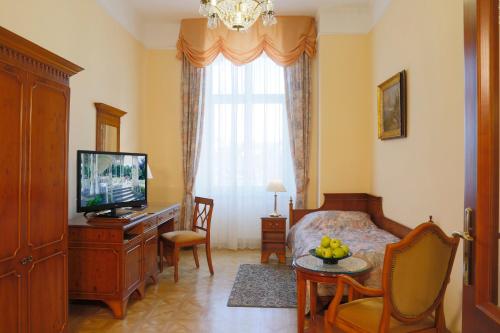 um quarto com uma cama, uma televisão e uma mesa em Bristol Kralovska Vila em Karlovy Vary