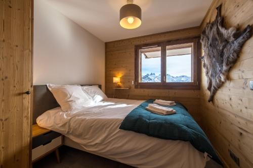 a bedroom with a bed and a window in it at ODYSSEE B102 Cosy appartement sur les pistes in La Toussuire