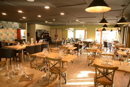 un restaurante lleno de mesas y sillas de madera en Premiere Classe Sete - Balaruc, en Balaruc-le-Vieux