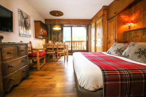 a bedroom with a bed and a table and chairs at Residence Hôtelière La Renardiere in Samoëns