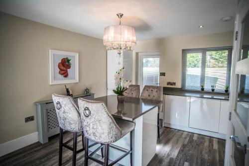a kitchen with a island with chairs and a chandelier at Courtyard Holiday Homes in Southport