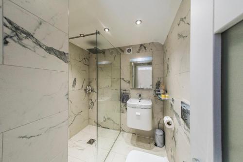 a bathroom with a toilet and a glass shower at Courtyard Holiday Homes in Southport