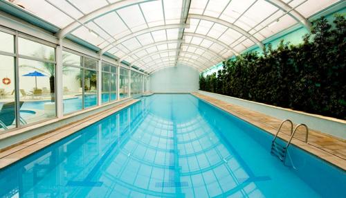 a large swimming pool with a glass ceiling and an indoor swimming pool at FLAT NA VILA OLÍMPIA ! ÓTIMA OPÇÃO ! in Sao Paulo
