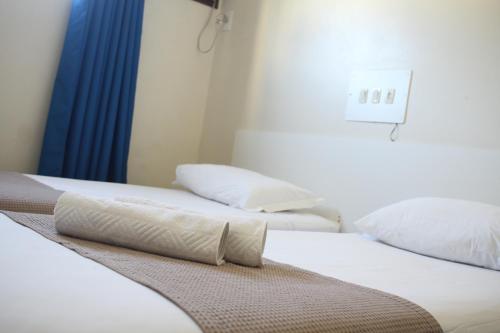 two beds with white sheets and pillows in a room at Hotel Marjaí in Itajaí