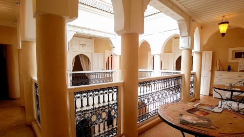 a large room with a balcony with a table at RIAD AWINATI Location Privatisée ,piscine chauffée in Marrakesh