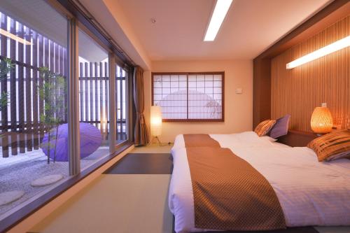 a bedroom with a bed and a large window at Kyoto Hana Hotel in Kyoto