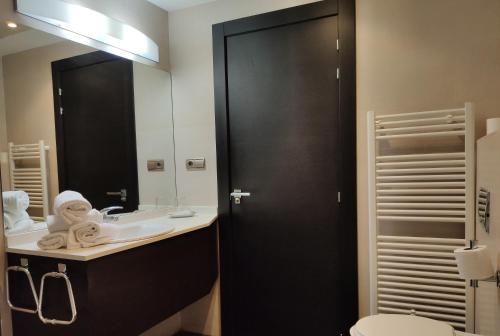 a bathroom with a sink and a toilet and a mirror at Hotel Rey Sancho in Navarrete