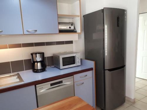 a kitchen with a stainless steel refrigerator and a microwave at Résidence Azuréa in Le Gosier