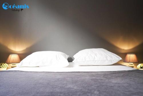 a bed with two white pillows and two lamps at Résidence Azuréa in Le Gosier