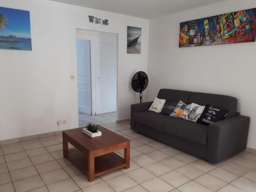 a living room with a black couch and a table at Résidence Azuréa in Le Gosier