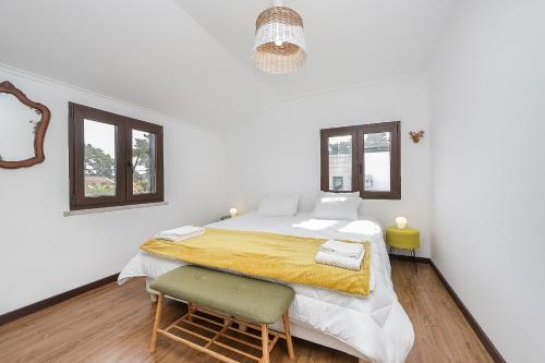 um quarto branco com uma cama grande e uma cadeira em Spacious Beach and Golf Villa em Charneca