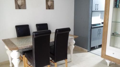 a dining room with a table and black chairs at Vacanza Complex in Benidorm