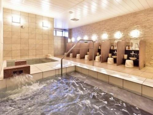 Hotel Frontier Iwaki / Vacation STAY 79262 في إيواكي: حوض استحمام مع نافورة مياه في الحمام
