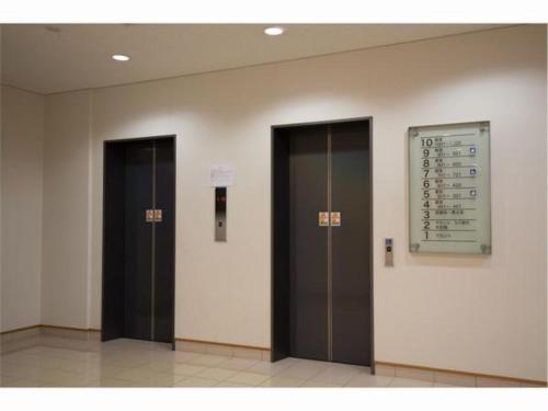 Hotel Frontier Iwaki / Vacation STAY 79262 في إيواكي: مصعدين في مبنى عليه لافته على الحائط