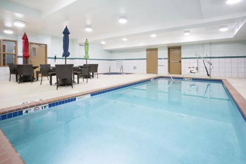 a swimming pool with tables and chairs in a building at Holiday Inn Express Hotel & Suites Minot South by IHG in Minot